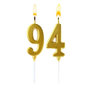 Beyaz arka planda 94 numarayı besteleyen altın renkli mumlar yakıyor. Doğum günü veya diğer özel tarihler için şenlik dekorasyonu