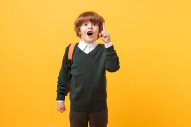 Sırt çantası ve turuncu arka plan kitabı olan tatlı bir okul çocuğu.