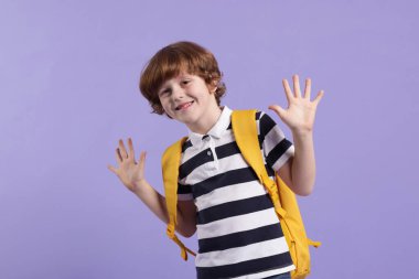 Menekşe arka planda sırt çantası olan tatlı bir okul çocuğu.