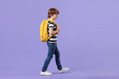 Menekşe arka planda sırt çantası olan tatlı bir okul çocuğu.