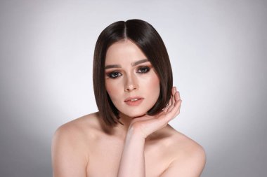 Açık gri arka planda muhteşem düz saçlı güzel bir genç kadının portresi.