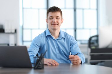 Ofiste masa başında çalışan yakışıklı adam.