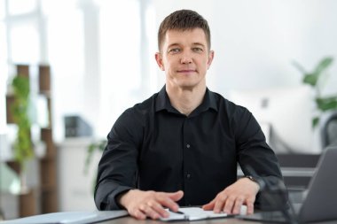 Ofiste masa başında çalışan yakışıklı adam.