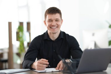 Ofiste masa başında çalışan yakışıklı adam.