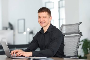 Ofiste masada dizüstü bilgisayarda çalışan adam