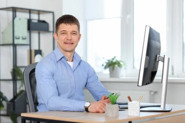 Ofiste masa başında çalışan yakışıklı adam.