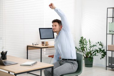 Ofiste sandalyeye uzanan yakışıklı adam.