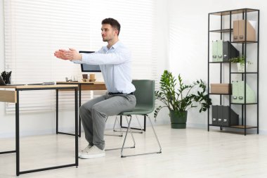 Ofiste sandalyeye uzanan yakışıklı adam.