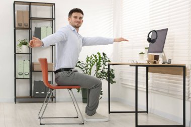 Ofiste sandalyeye uzanan yakışıklı adam.