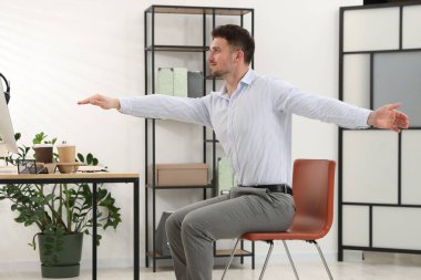 Ofiste sandalyeye uzanan yakışıklı adam.