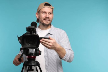 Açık mavi arkaplanda profesyonel video kamerası olan adam, metin için boşluk