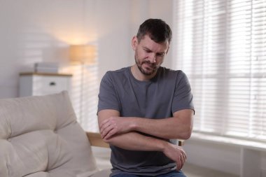 Evde dirsek ağrısı çeken bir adam var.