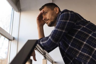 Binanın penceresinin yanında depresif bir adam var. Zihinsel sağlık sorunu