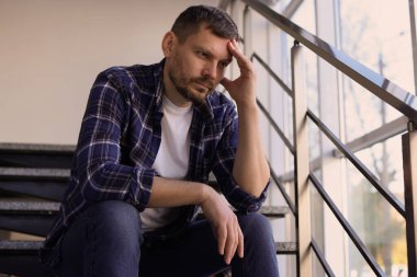 Binanın merdivenlerinde oturan bunalımlı adam.