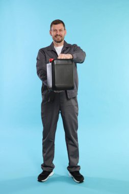 Açık mavi arka planda plastik kutu tutan adam.