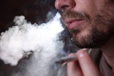 Arka planda sigara içen adam, yakın plan.