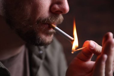 Arka planda kibrit yakan adam, yakın plan.