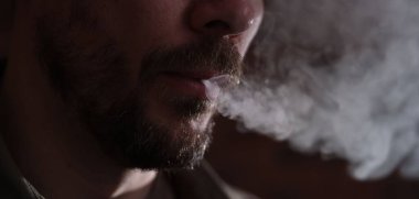 Arka planda sigara içen adam, yakın plan görünümü