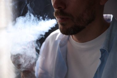 Arka planda sigara içen adam, yakın plan.