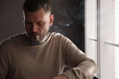 Odada sigara içen bir adam var.