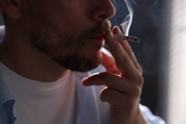 Arka planda sigara içen adam, yakın plan.