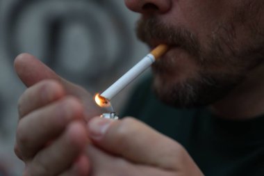 Arka planda sigara yakan adam, yakın plan.