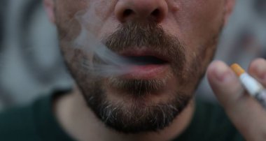 Arka planda sigara içen adam, yakın plan.