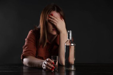 Alkol bağımlılığı. Masasında votka olan sefil bir kadın.