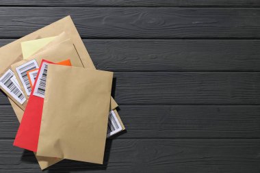 Postane. Gri ahşap masadaki farklı kağıt zarflar, üst manzara. Metin için boşluk