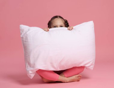 Pembe arka planda yastığı olan tatlı bir kız.