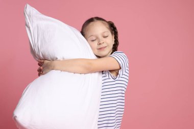 Pembe arka planda yastığı olan tatlı bir kız.