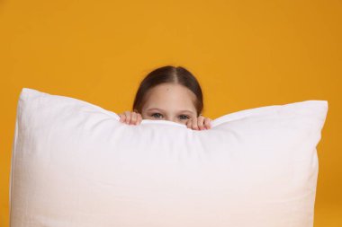 Turuncu arka planda yastığı olan tatlı bir kız.