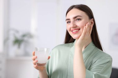 Arka planda bir bardak kolajen suyu olan gülümseyen kadın.