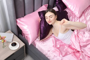 Yatakta ipek çarşaflarla uzanan bir kadın.