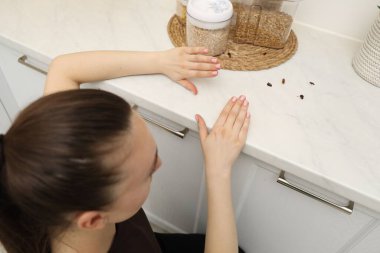 Mutfak tezgahında hamamböceklerine bakan bir kadın.