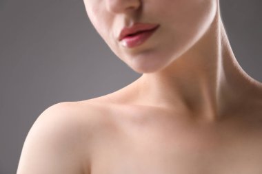 Gri arka planda güzel köprücük kemikleri ve boynu olan kadın, yakın plan.