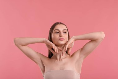 Pembe arka plandaki epilasyondan sonra pürüzsüz bir ten gösteren genç kadın.