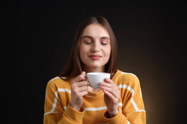 Kahverengi arka planda kahve fincanı olan bir kadın.