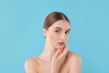 Açık mavi arka planda büyüleyici genç bir kadının portresi.