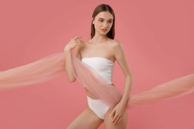 Pembe arka planda güzel kumaşlı genç bir kadın.