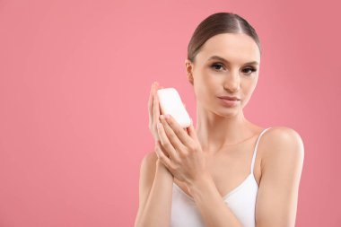 Pembe arka planda sabun çubuğu olan güzel bir kadın. Metin için boşluk