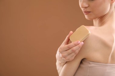 Kahverengi arka planda sabun barı olan bir kadın, yakın plan. Metin için boşluk