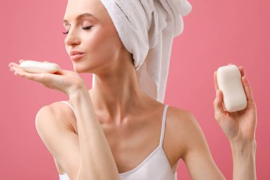 Pembe arka planda sabun çubukları olan güzel bir kadın.