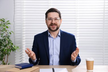 Gülümseyen çevrimiçi hoparlör. İçerideki masada web kamerasından görüntüsü olan webinar.