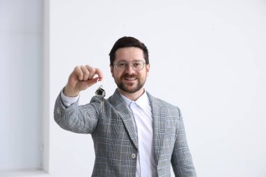 Emlakçının elinde ev şeklindeki anahtarlık var.