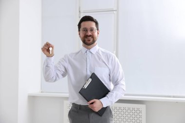 Emlakçının elinde evin anahtarı, anahtarlık ve pano var.