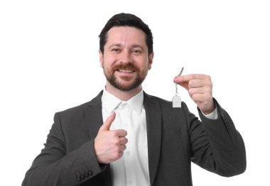 Ev şekilli anahtarlığı olan ve beyaz arka planda baş parmak gösteren bir emlakçı.