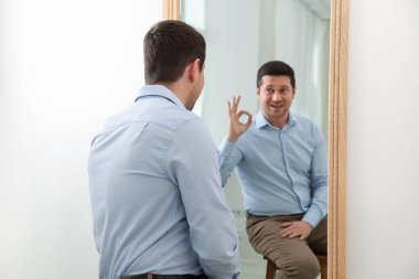 Yakışıklı adam aynanın yanında iyi niyet gösterisi yapıyor.