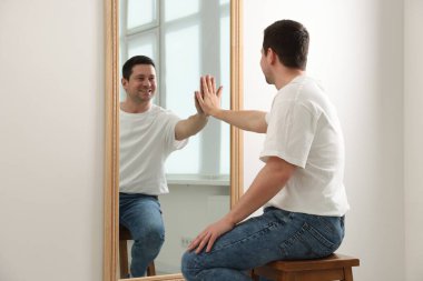 Yakışıklı adam aynada kendine bakıyor.