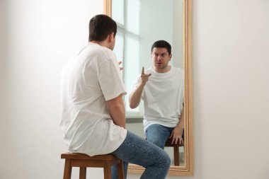 Yakışıklı adam aynada kendine bakıyor.